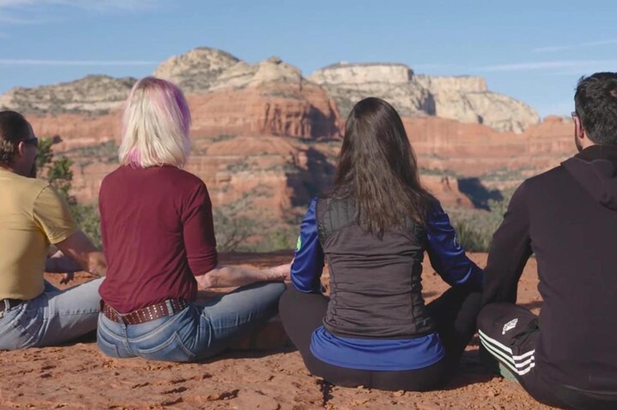 a group of people sitting on the rim of a canyon