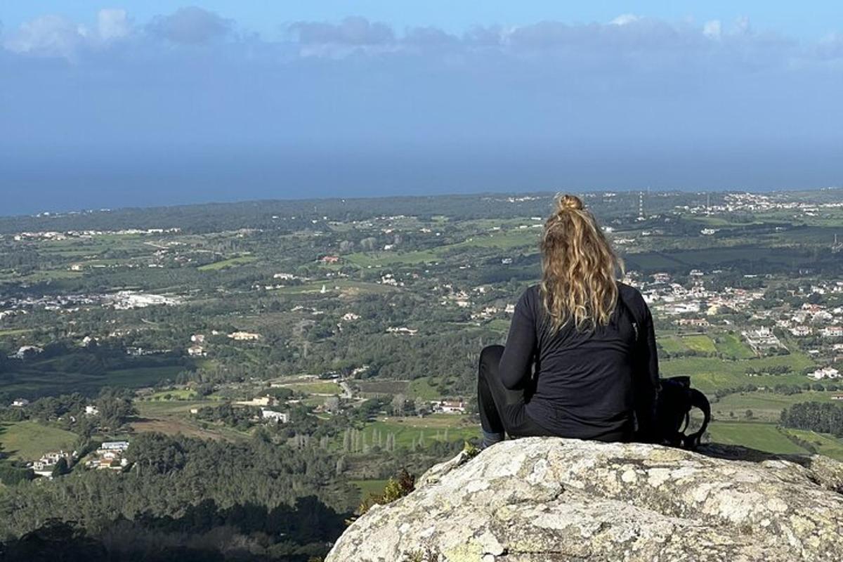 una persona seduta in cima a una roccia che guarda una città