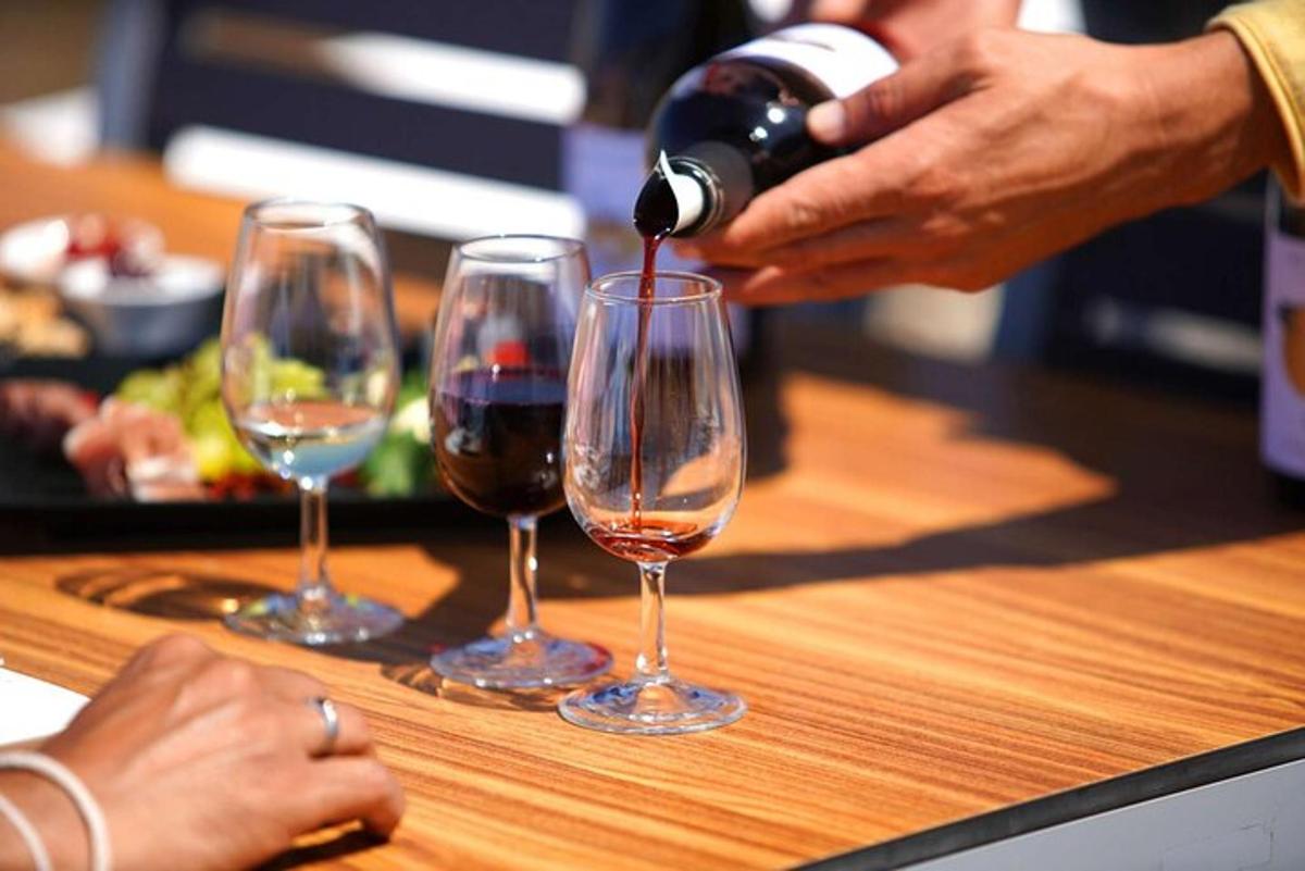 una persona che versa il vino in tre bicchieri da vino