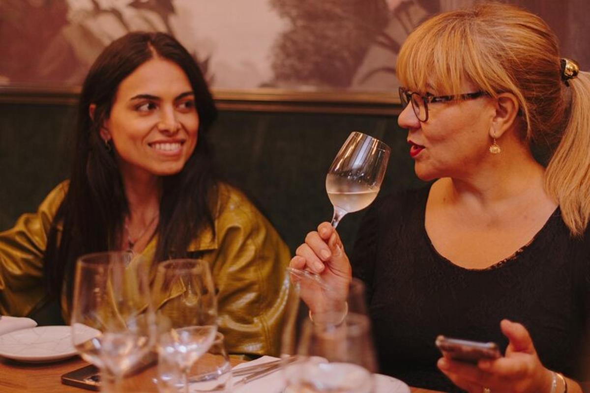 due donne sedute a un tavolo con un bicchiere di vino