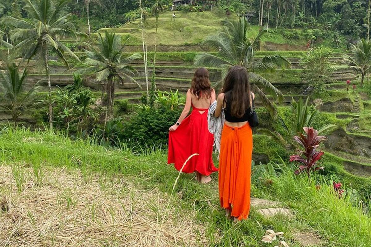 dua wanita berjalan menyusuri jalan setapak sambil melihat bukit
