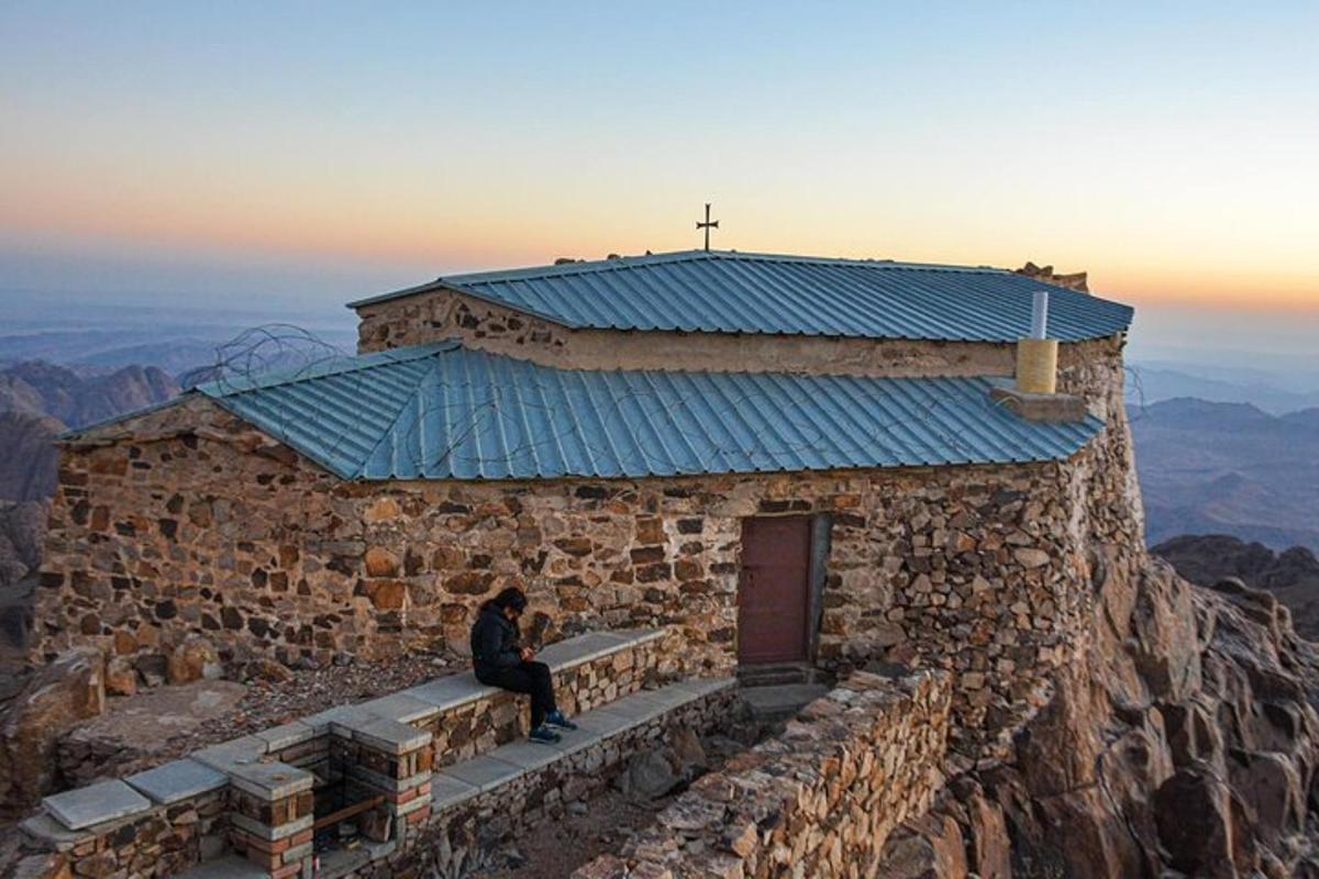 osoba sedící na lavičce před budovou