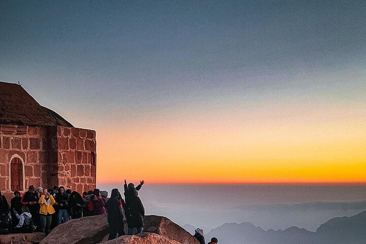 un grup de oameni care stau pe vârful unui munte la apus