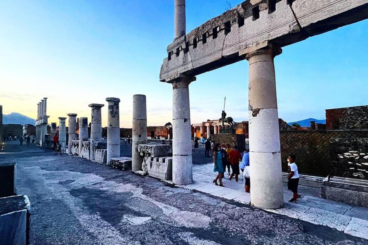 Un grupo de personas caminando alrededor de un edificio con columnas.