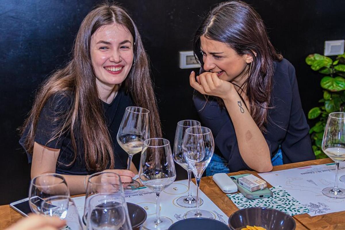 dve ženski, ki sedita za mizo z vinskimi kozarci