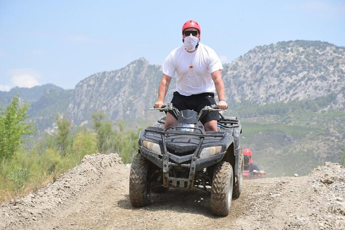 muž s rouškou jedoucí na čtyřkolce na hoře
