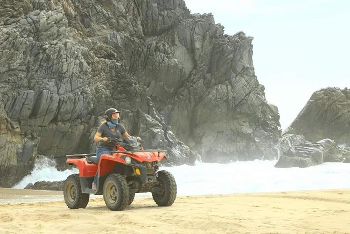 une personne conduisant un quad sur la plage