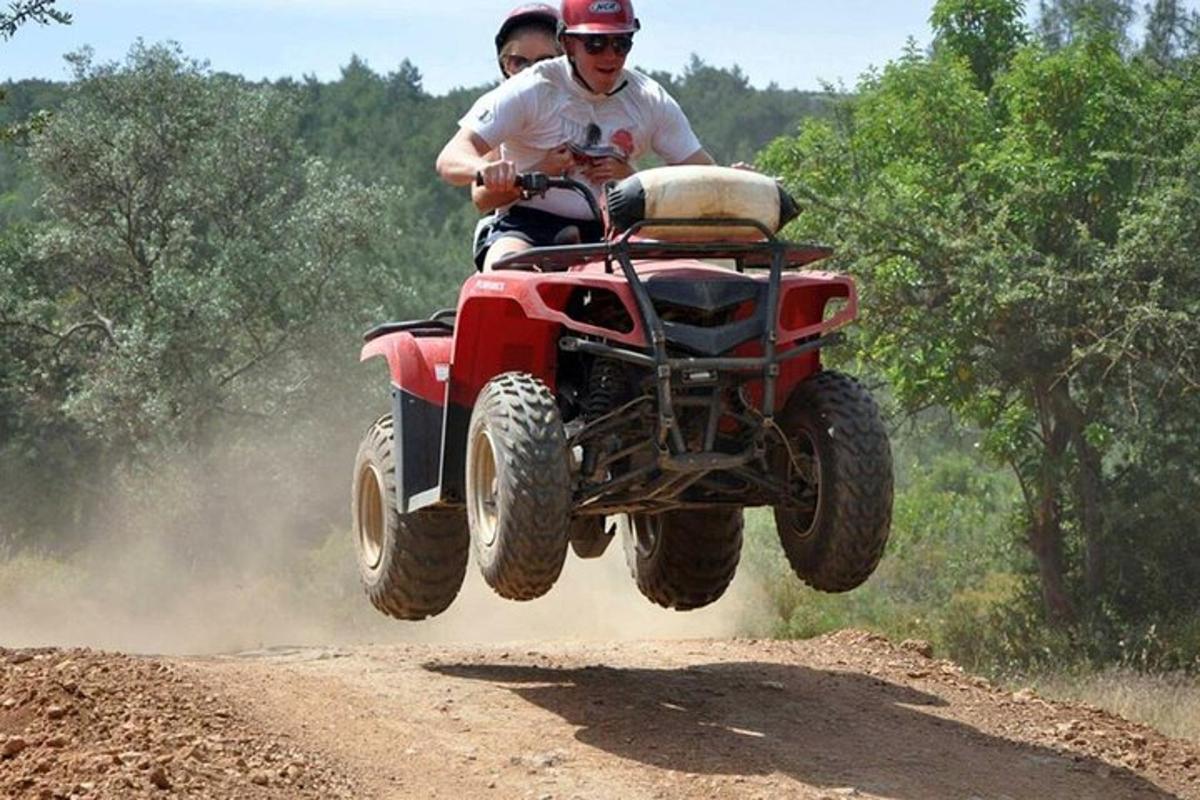 dva lidé jedoucí na čtyřkolce po nezpevněné cestě