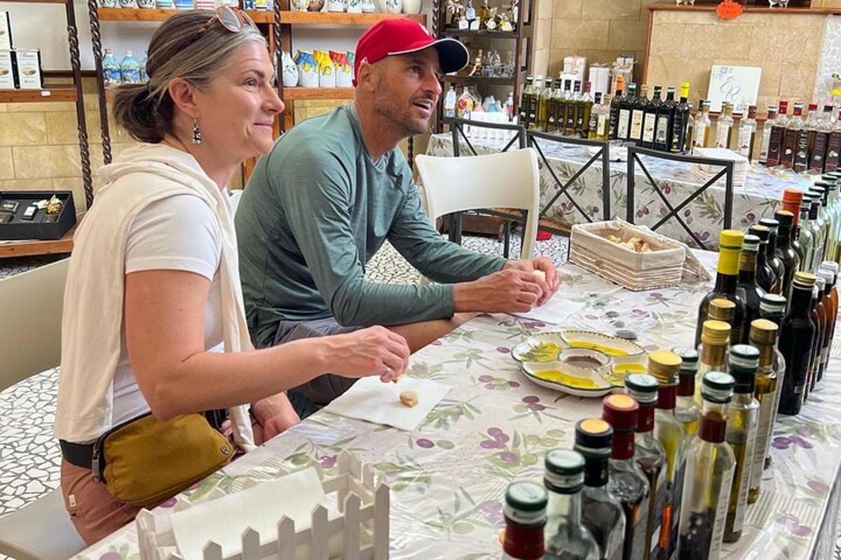 un uomo e una donna seduti a un tavolo con bottiglie di vino