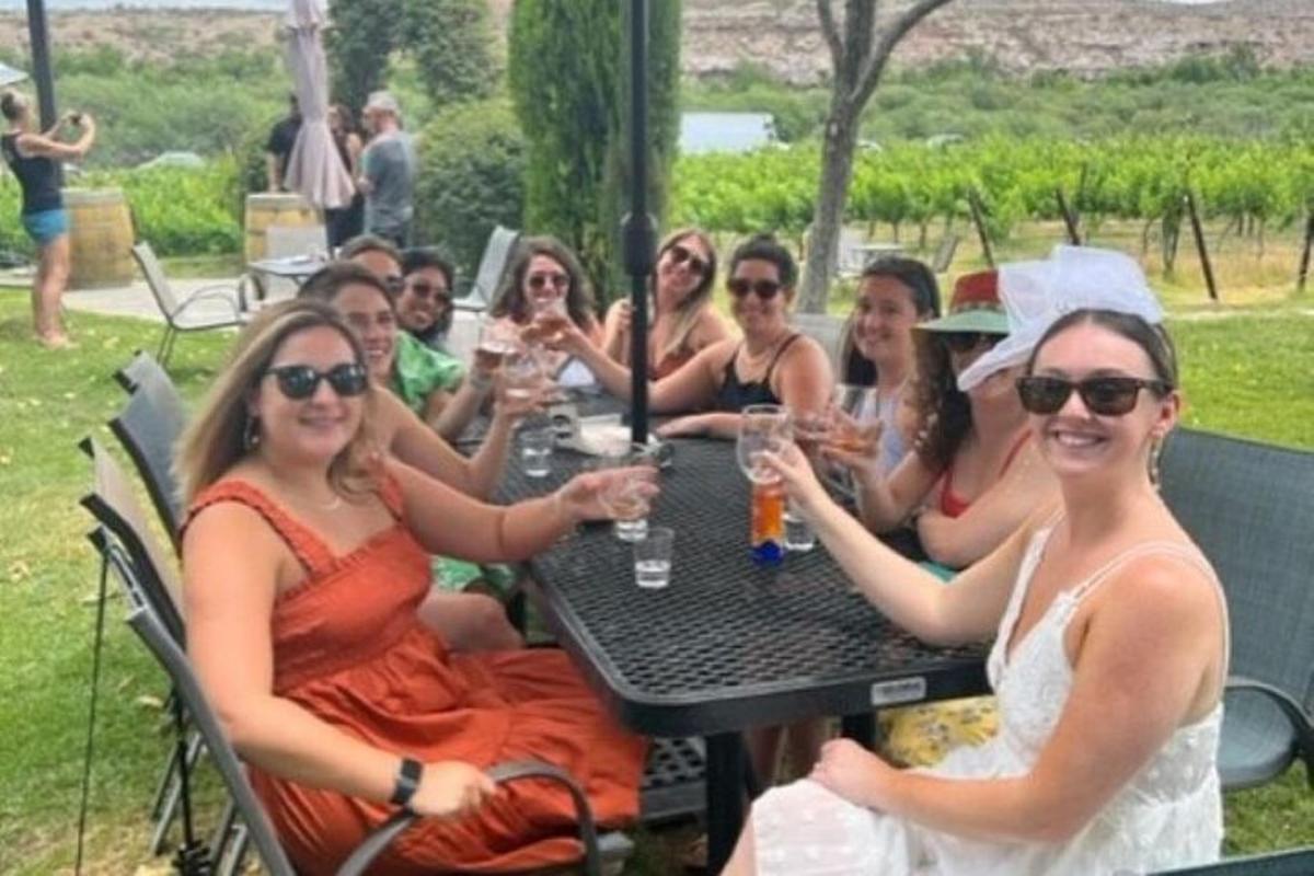 een groep vrouwen die aan een tafel zitten met wijnglazen