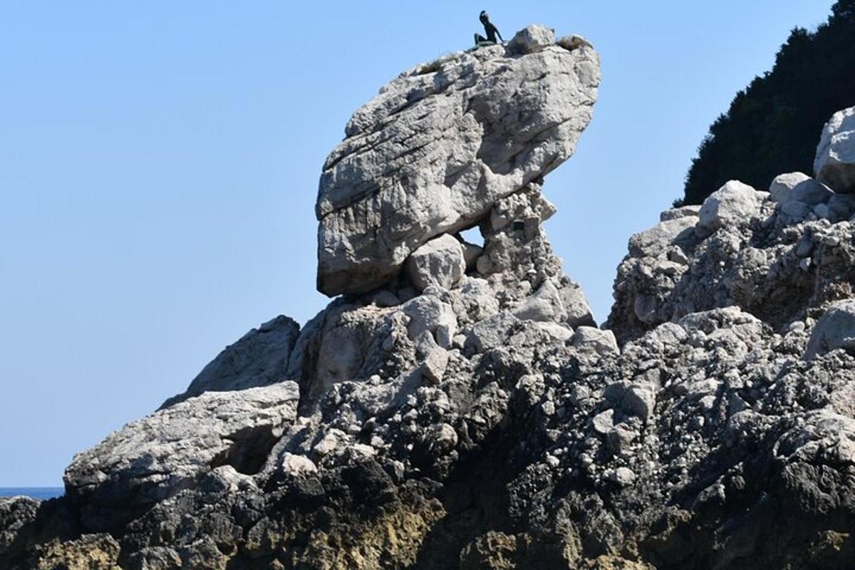 una persona seduta in cima a una grande roccia