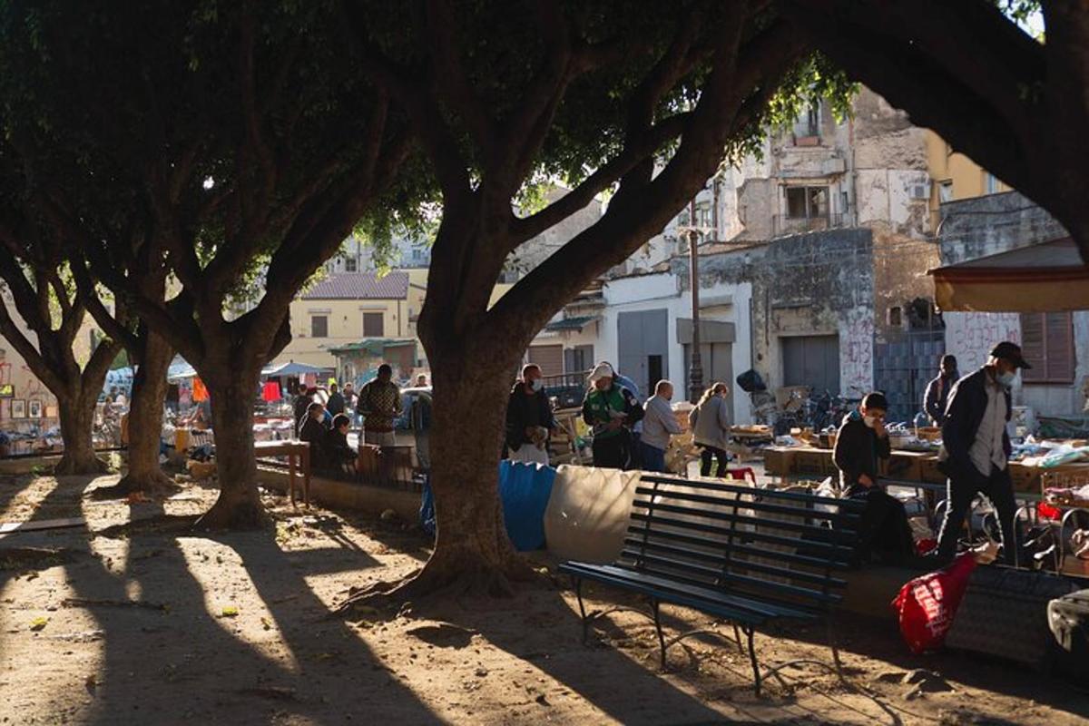 ένα πάρκο με ένα παγκάκι και δέντρα και ένα πλήθος ανθρώπων