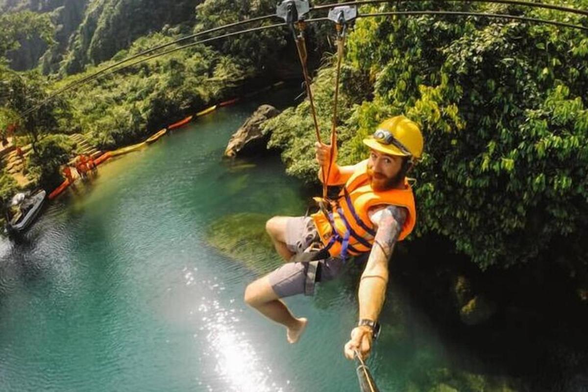 một người đàn ông đang treo mình trên một sợi dây thừng qua sông