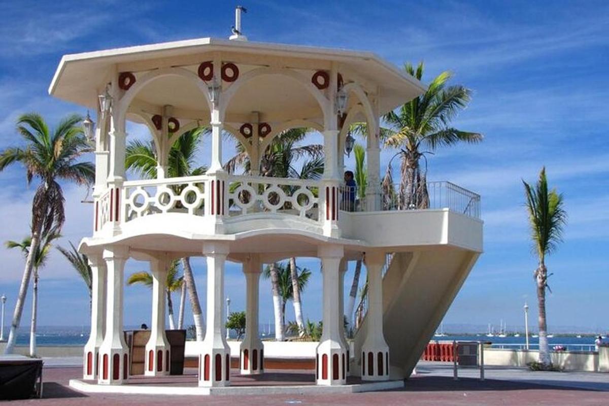a white gazebo on the beach with palm trees