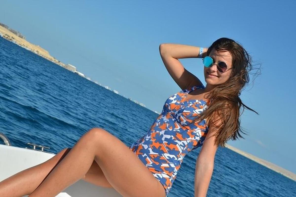 una dona amb banyador i ulleres de sol asseguda en un vaixell