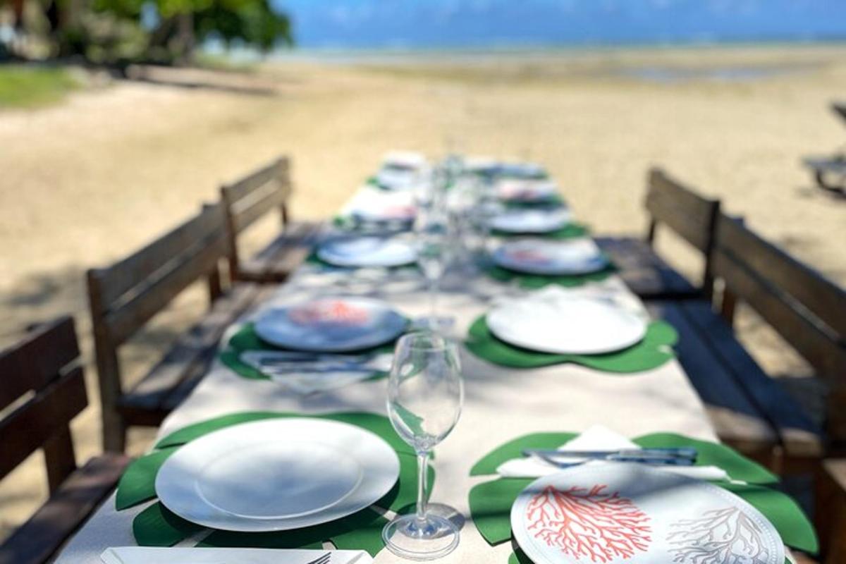 uma longa mesa com pratos e copos na praia