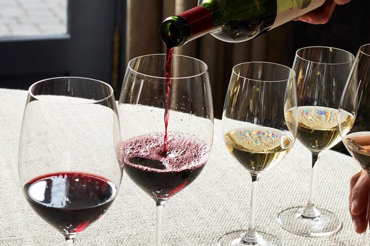osoba nalewająca czerwone wino do trzech kieliszków