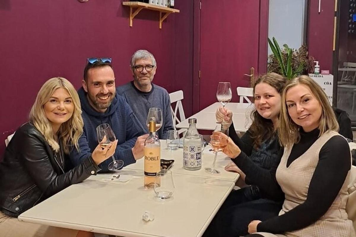 un gruppo di persone sedute a un tavolo con bicchieri di vino