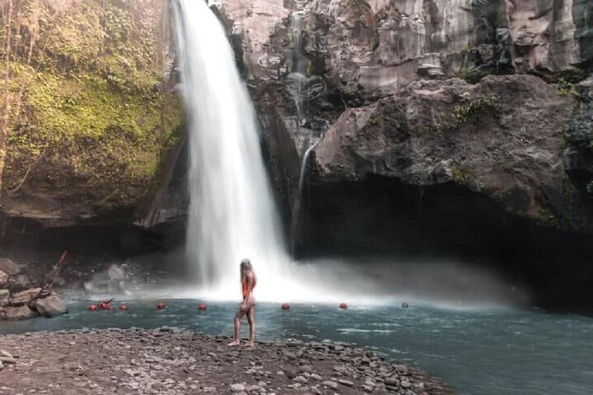 a woman standing in front of a waterfall