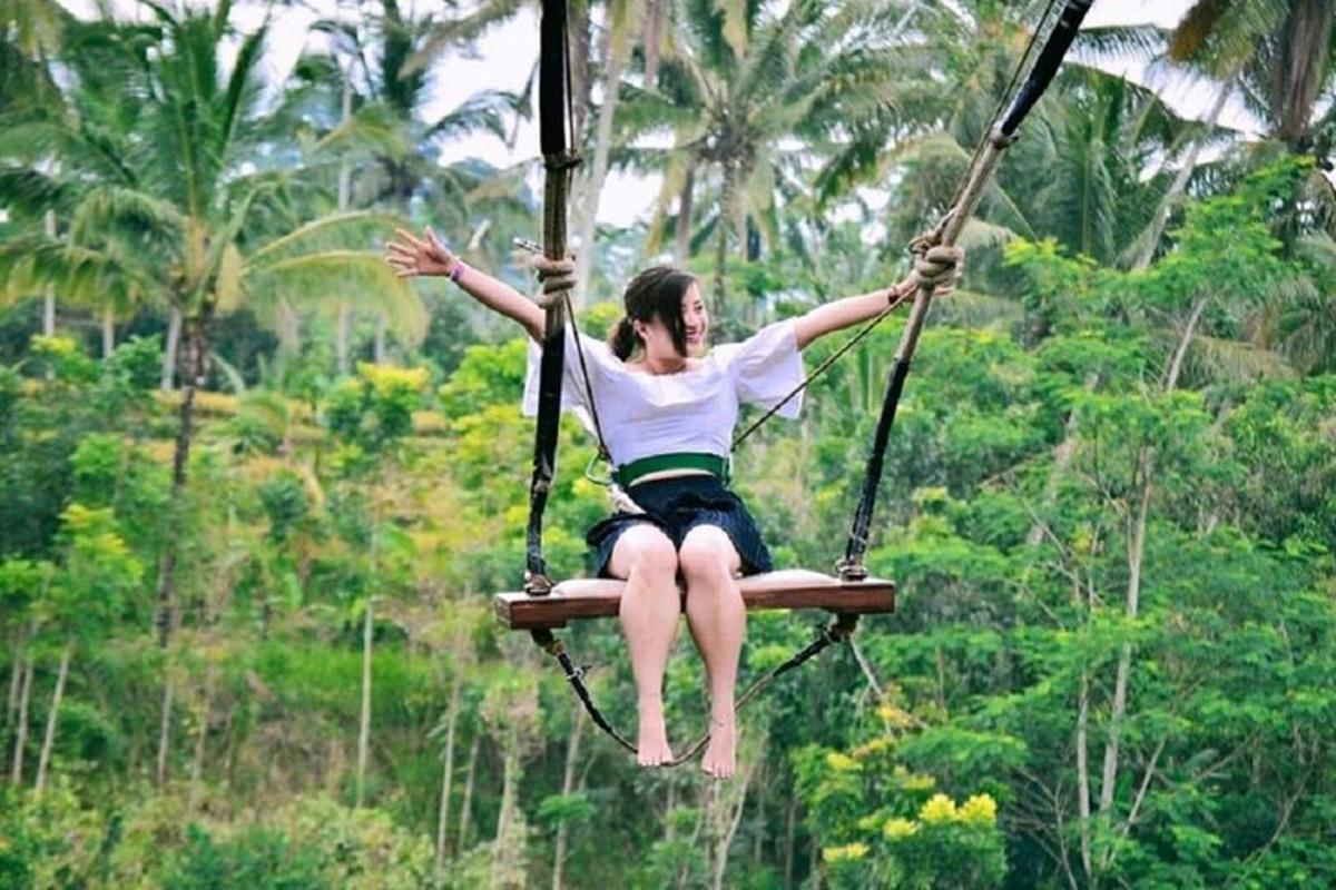 a woman sitting on a swing in the jungle