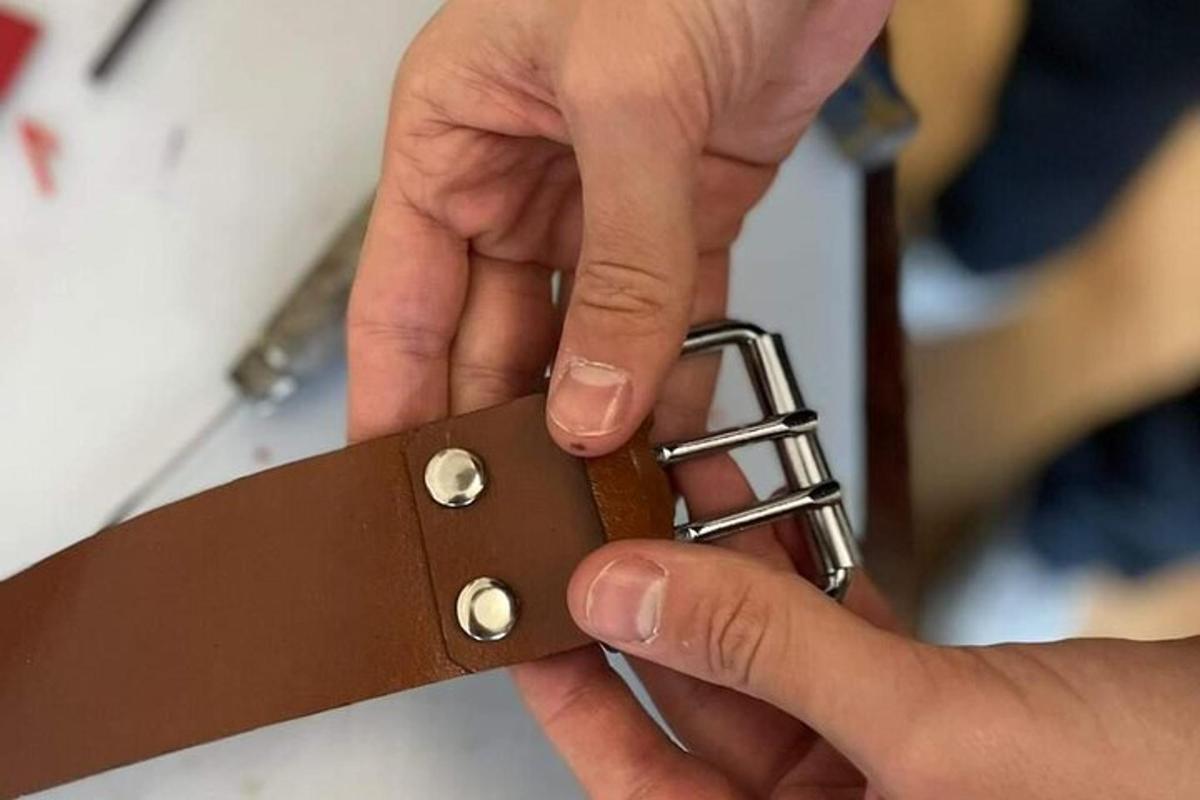 una persona tiene in mano una cinghia marrone su un coltello