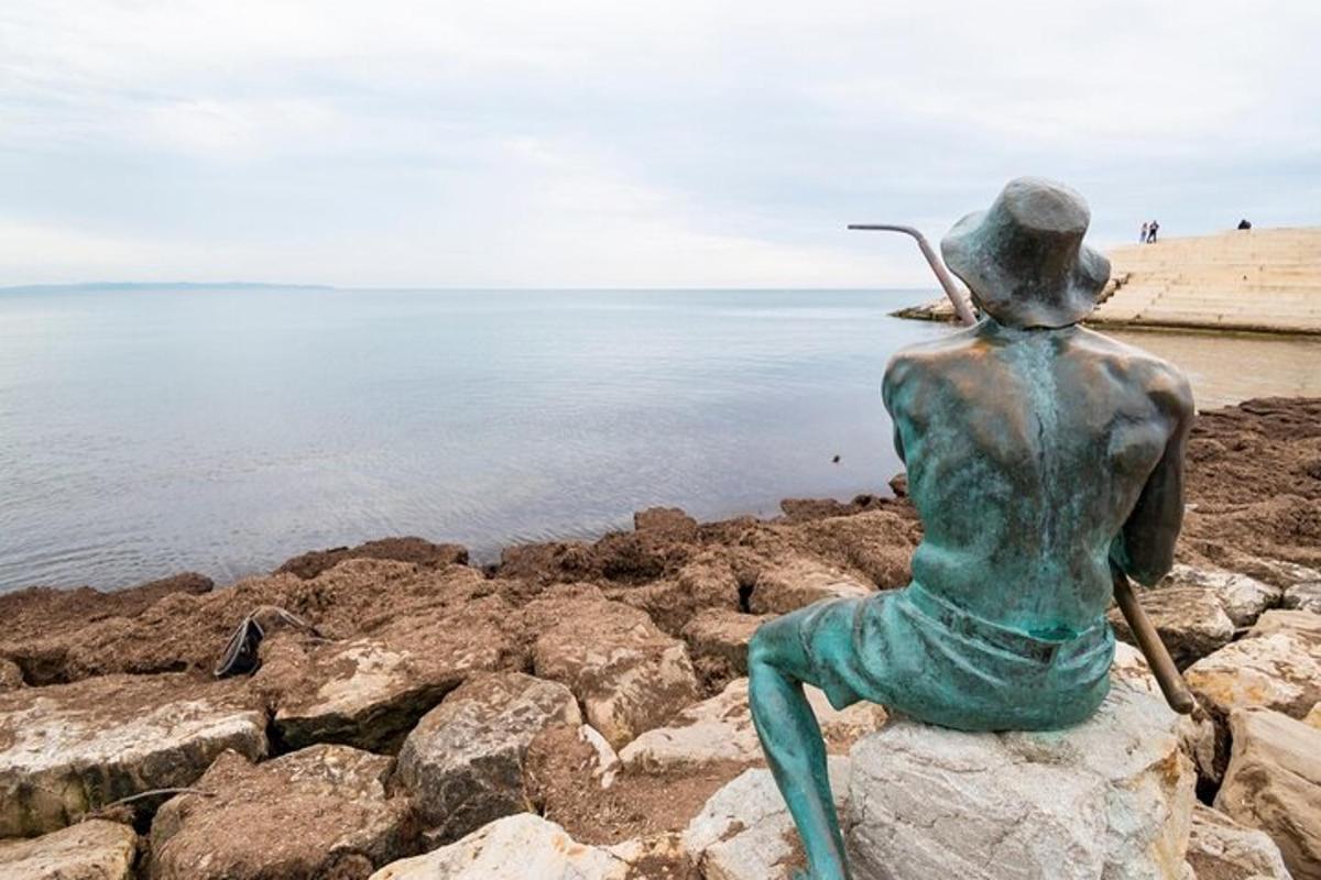 egy nő szobra, amely egy sziklán ül a vízparton