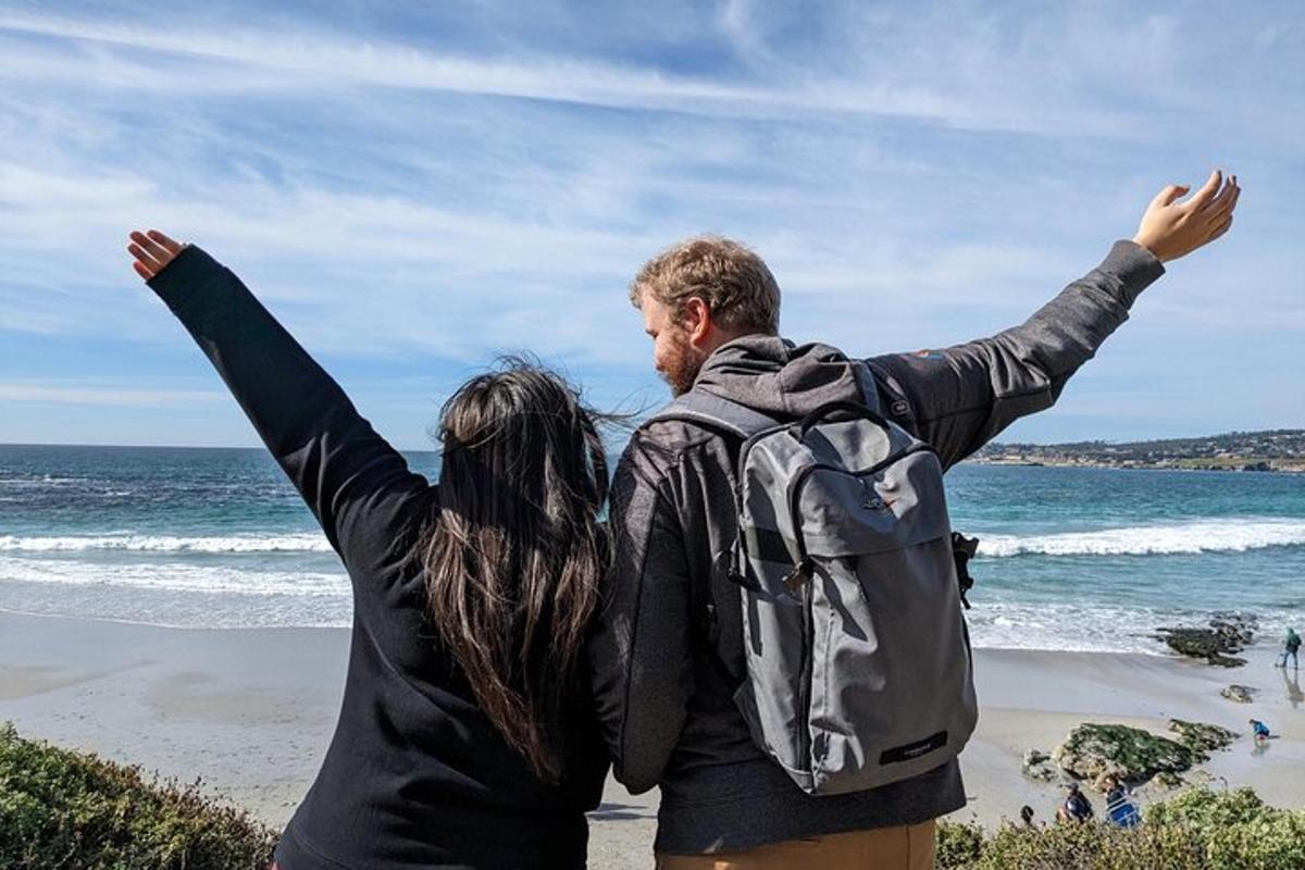 um homem e uma mulher em pé na praia com os braços levantados