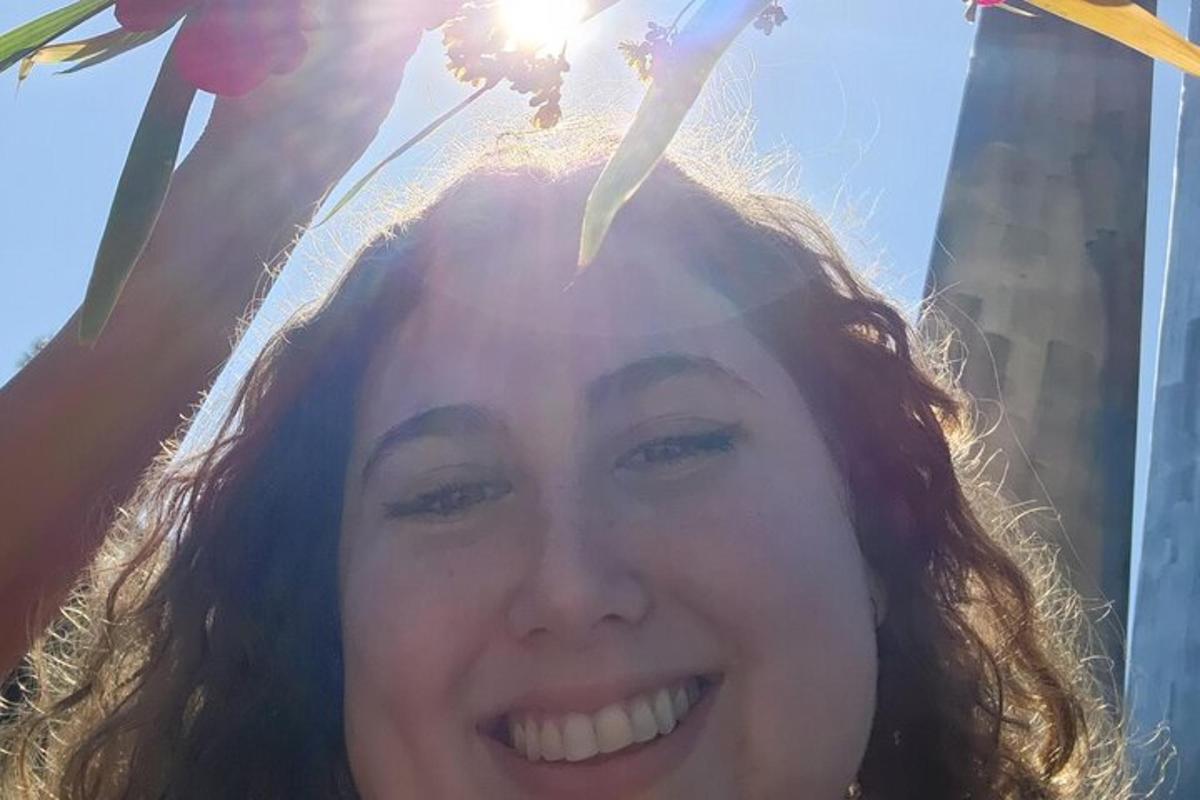 a woman is smiling with the sun on her head