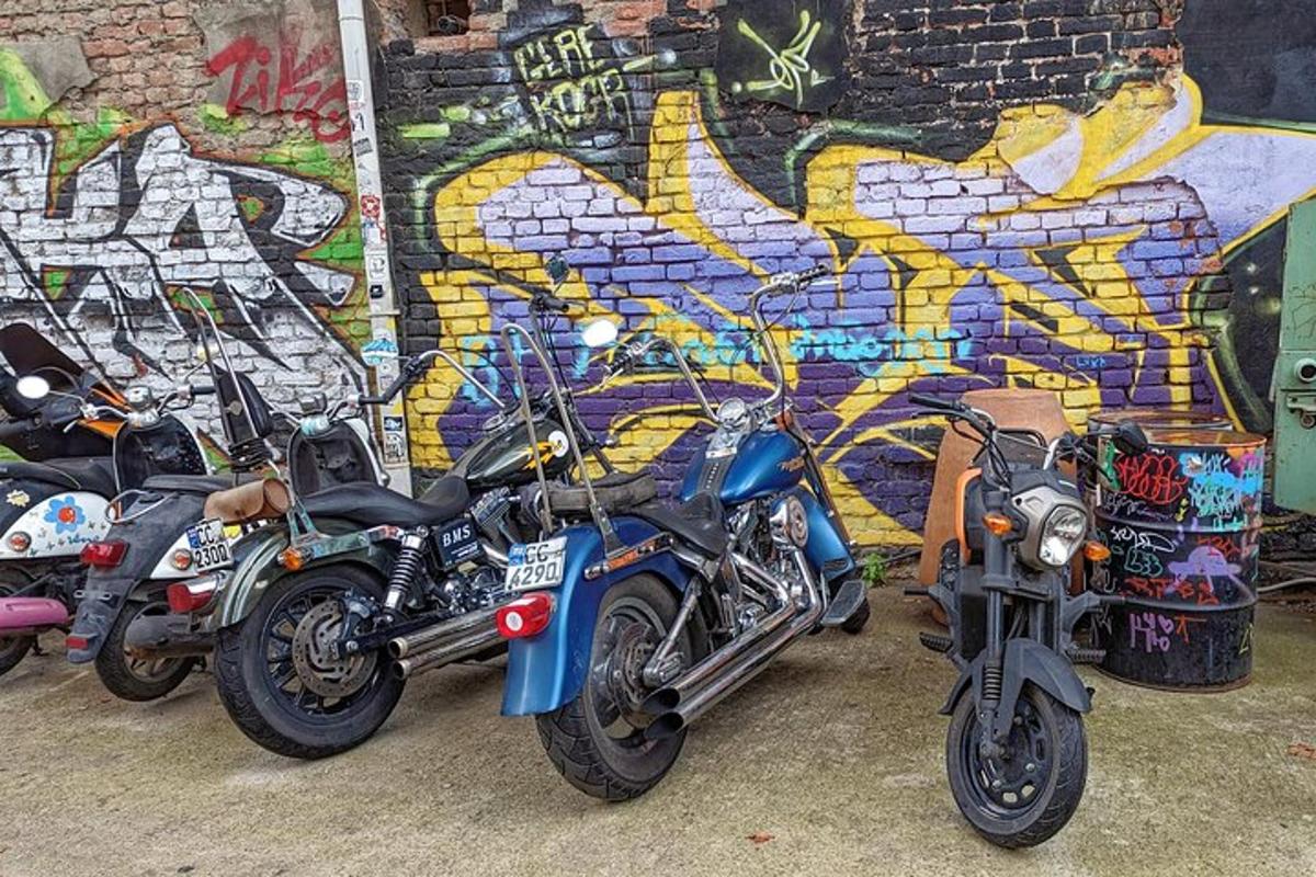 fire motorsykler parkert foran en vegg med graffiti