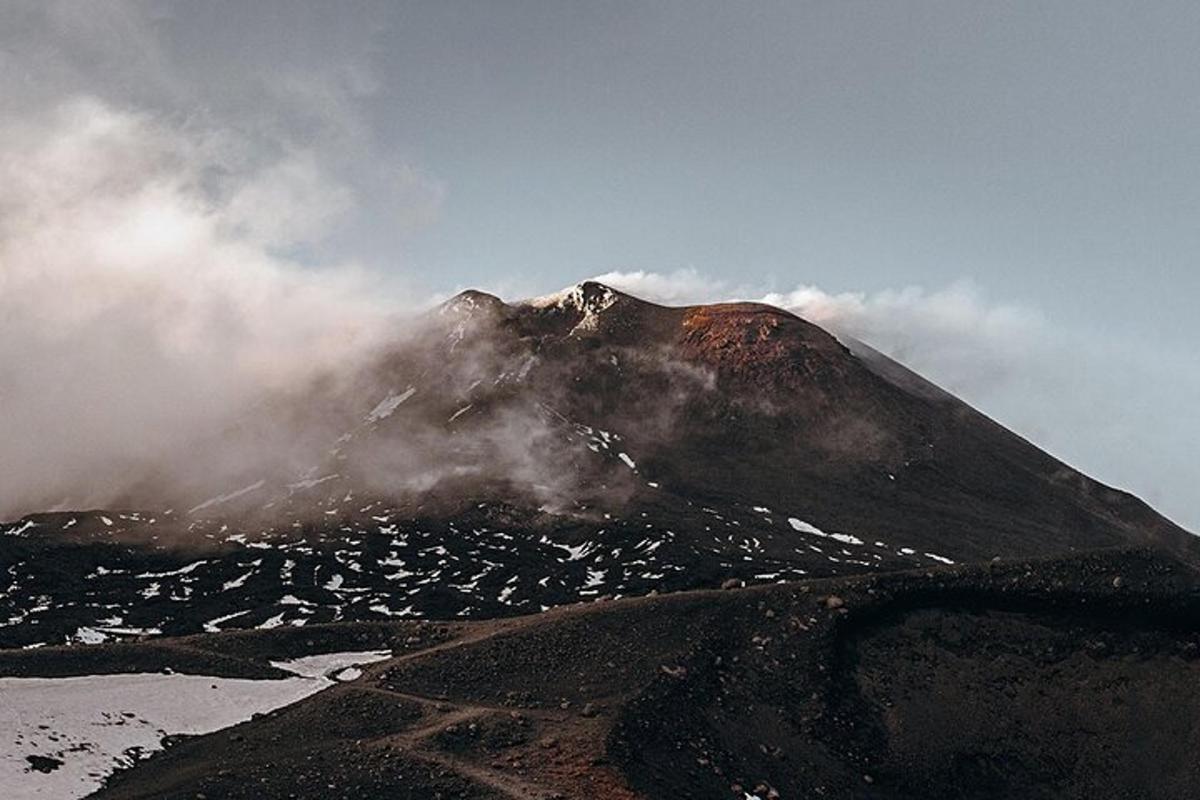 et fjell dekket av tåke og skyer på et fjell