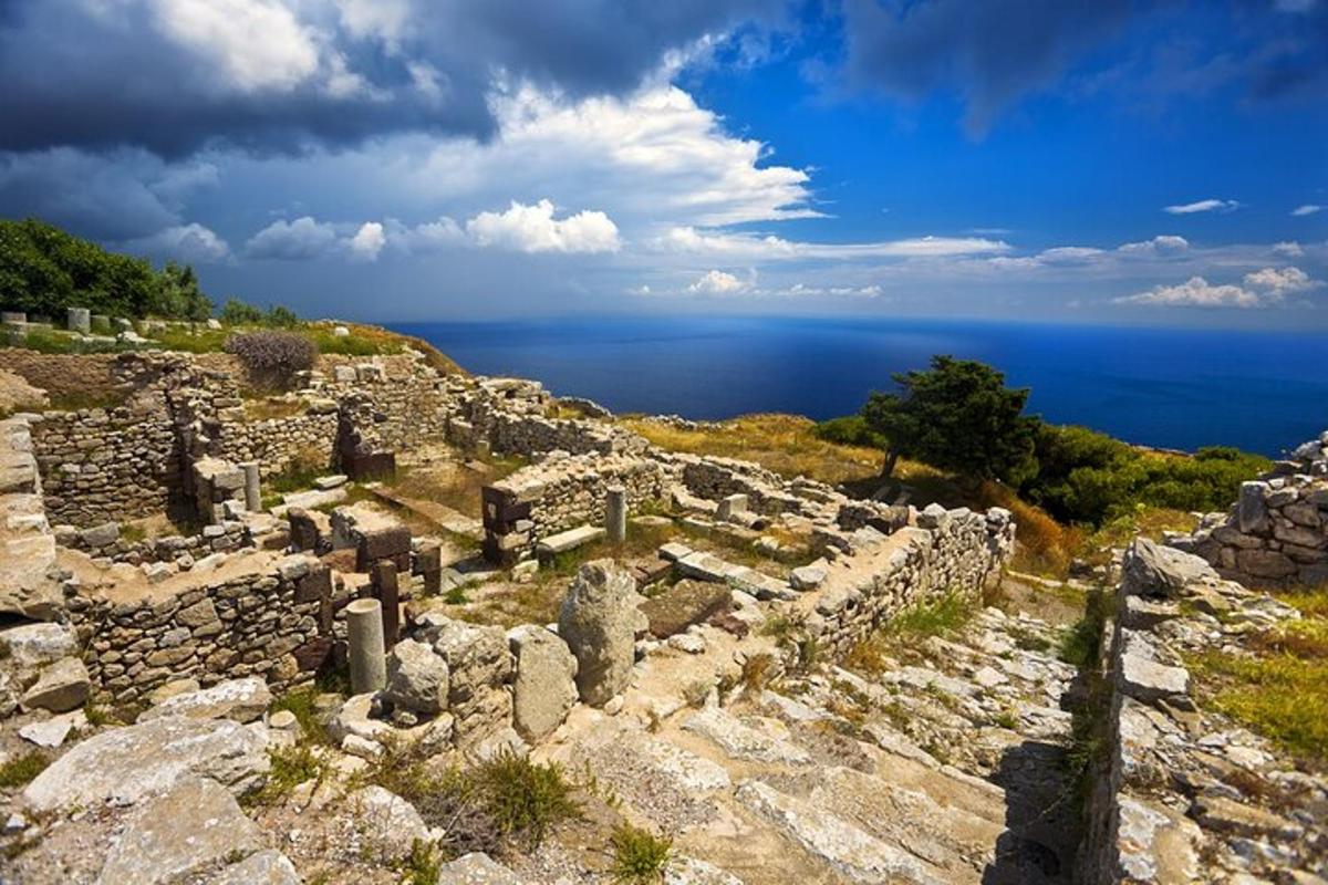 ancient ruins on a hill with the ocean in the background