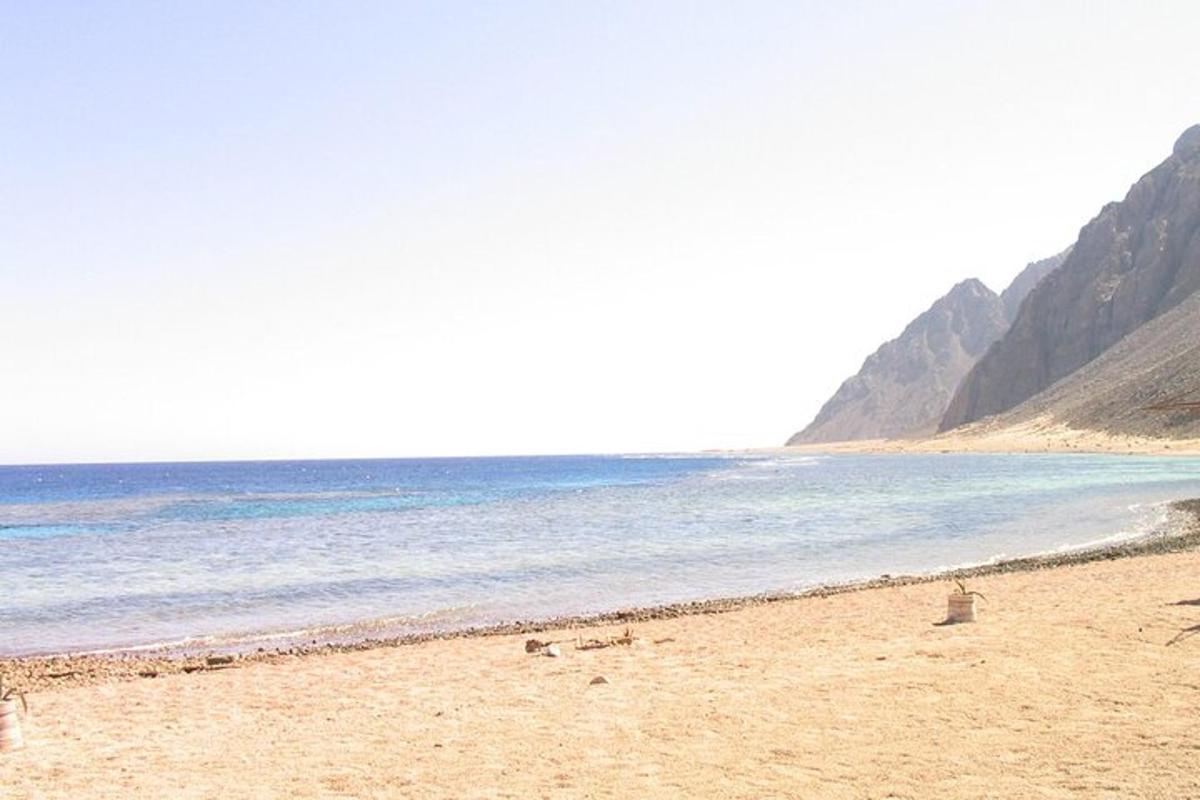 een strand met de oceaan en de bergen op de achtergrond