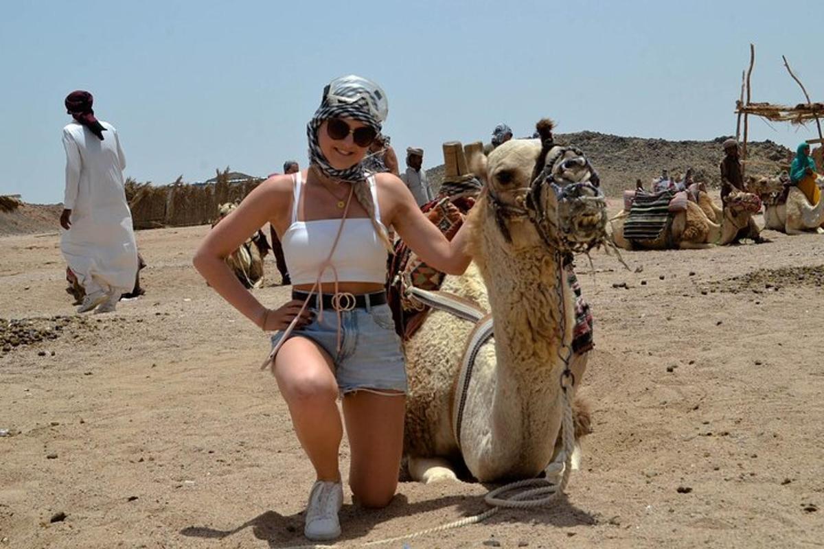a woman in a bikini standing next to a camel