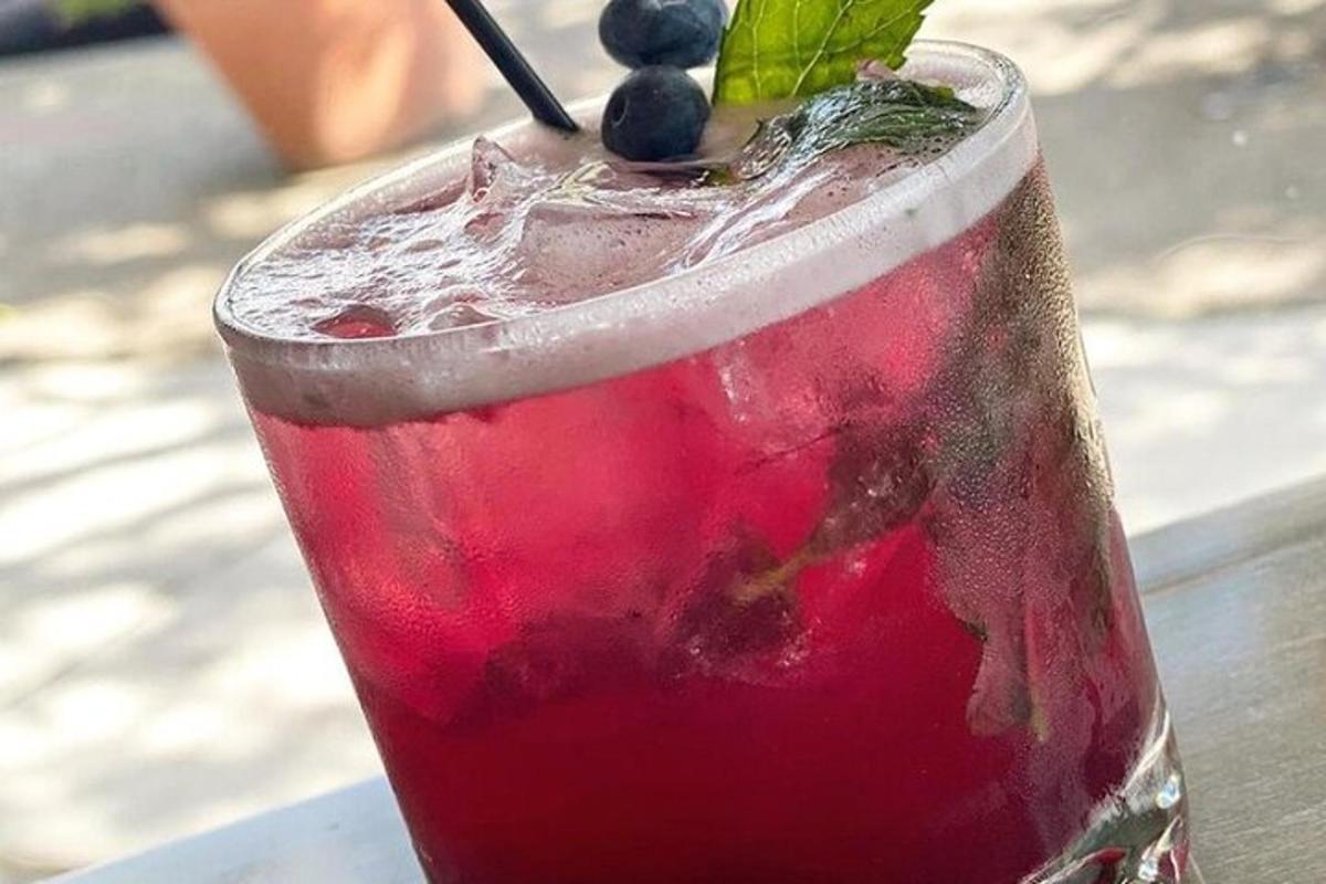 a red drink with a blueberry on a table