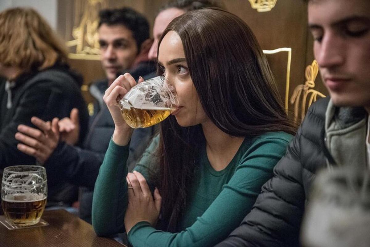 una dona bevent un got de cervesa a una taula