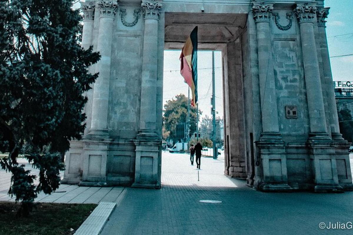a person riding a bike under a building with a flag