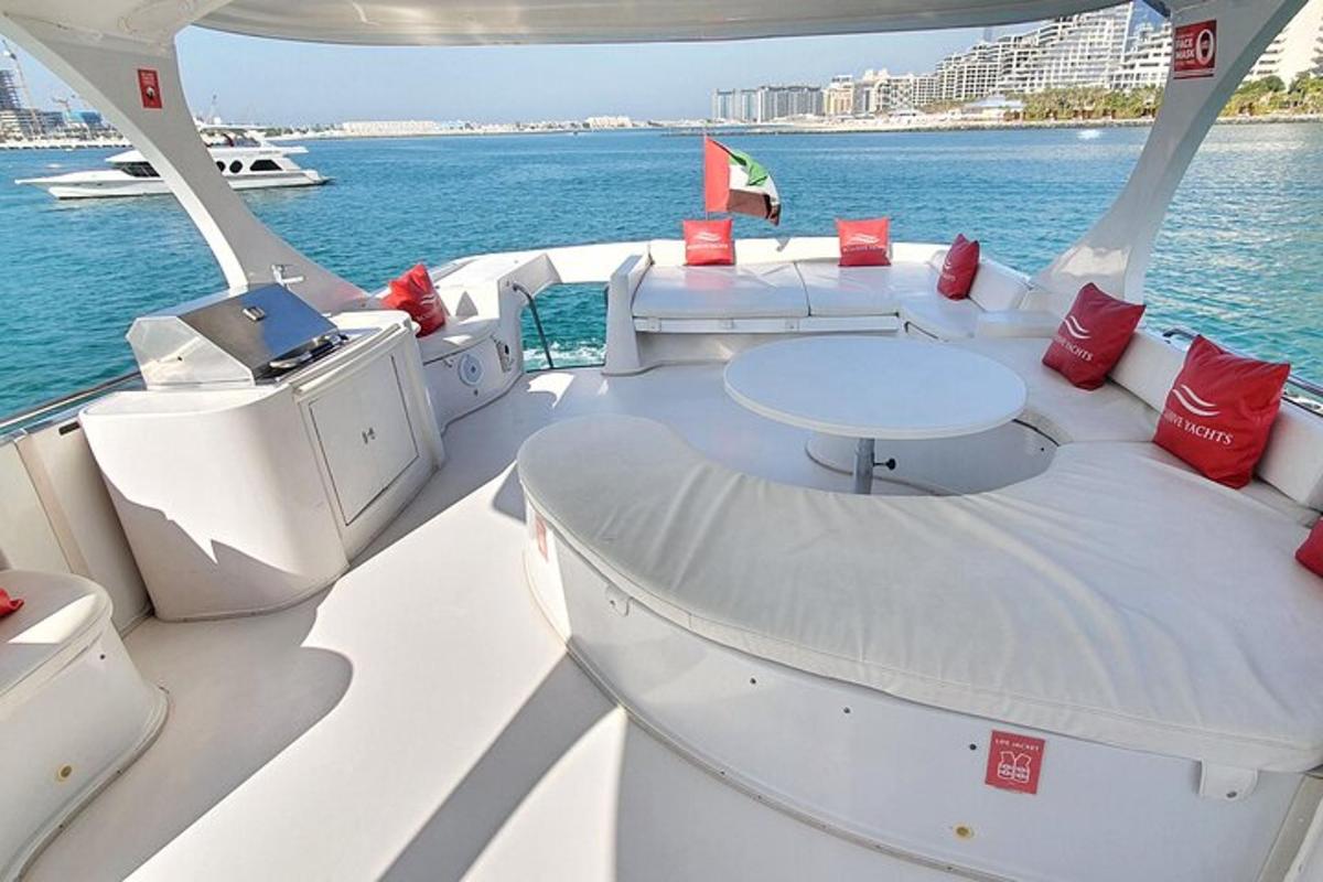 a white boat with red pillows and a table on the water