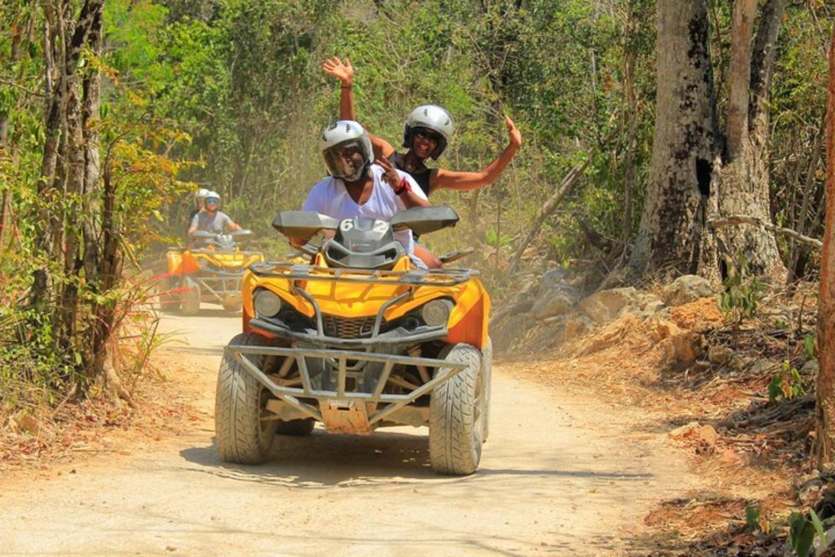 Dos personas en un vehículo de cuatro ruedas por un camino de tierra