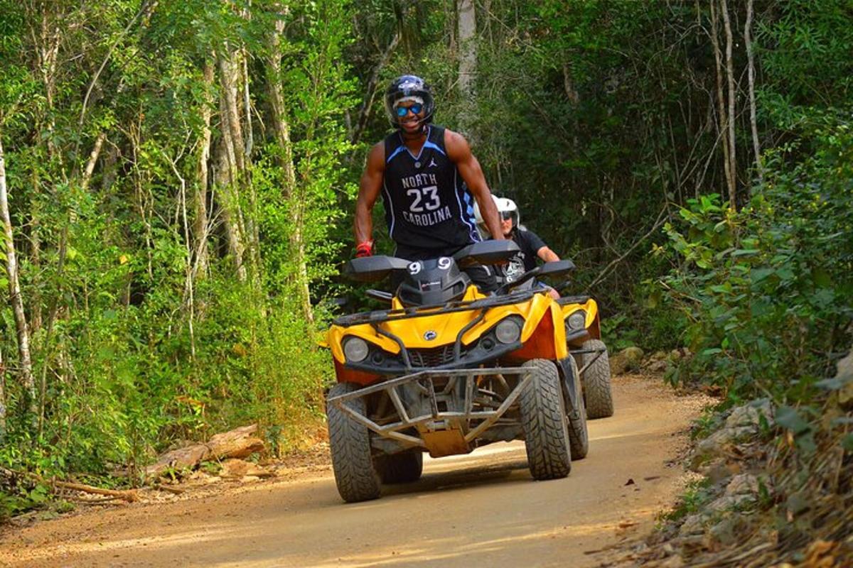 un home que viatja en un quad per una carretera de terra
