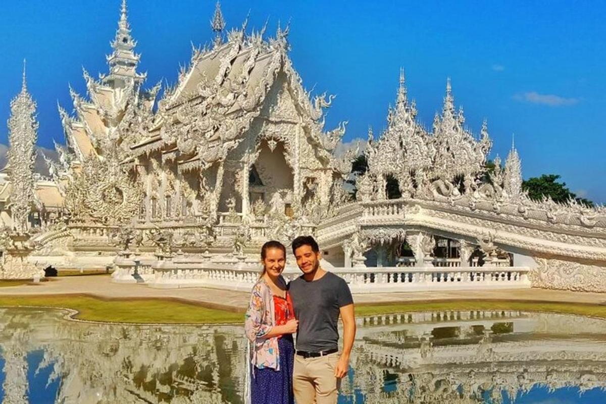 một người đàn ông và một người phụ nữ tạo dáng trước một ngôi đền trắng