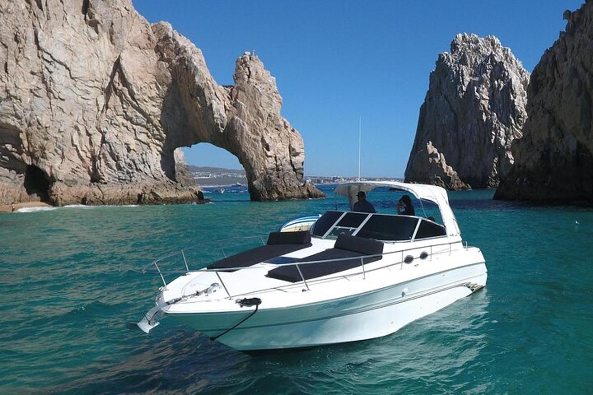 um barco branco na água em frente a uma formação rochosa