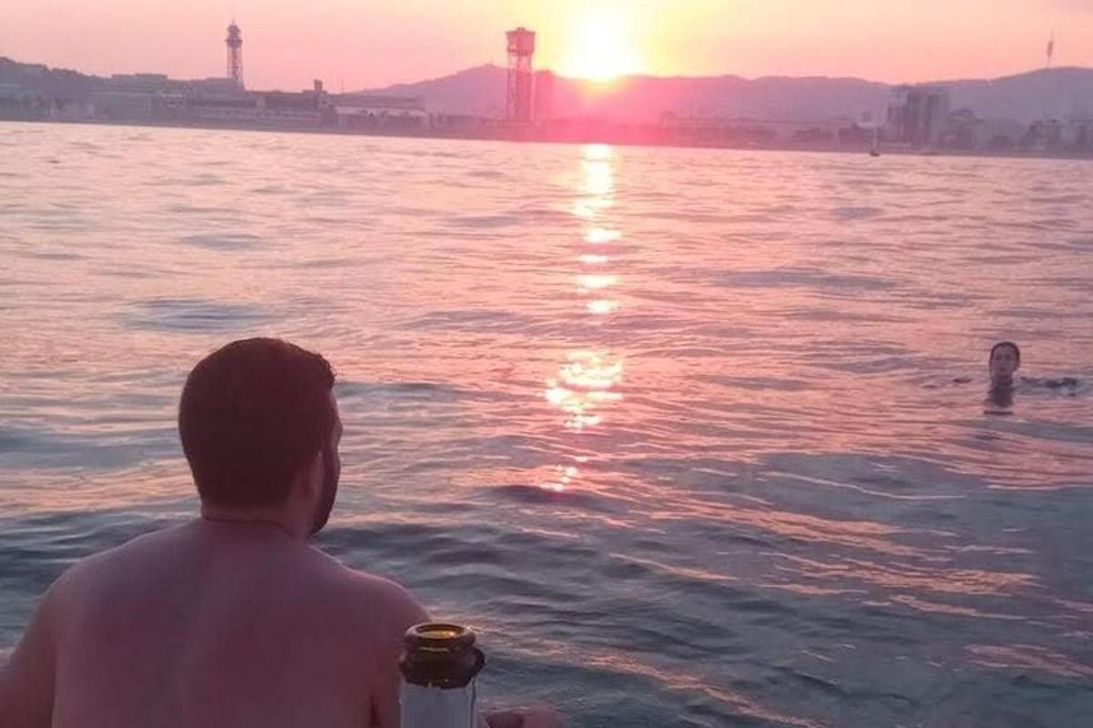 ένας άντρας που κάθεται στο νερό και παρακολουθεί το ηλιοβασίλεμα