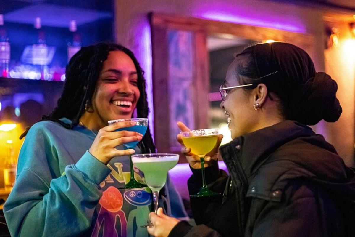 due donne sorridono e bevono cocktail in un bar