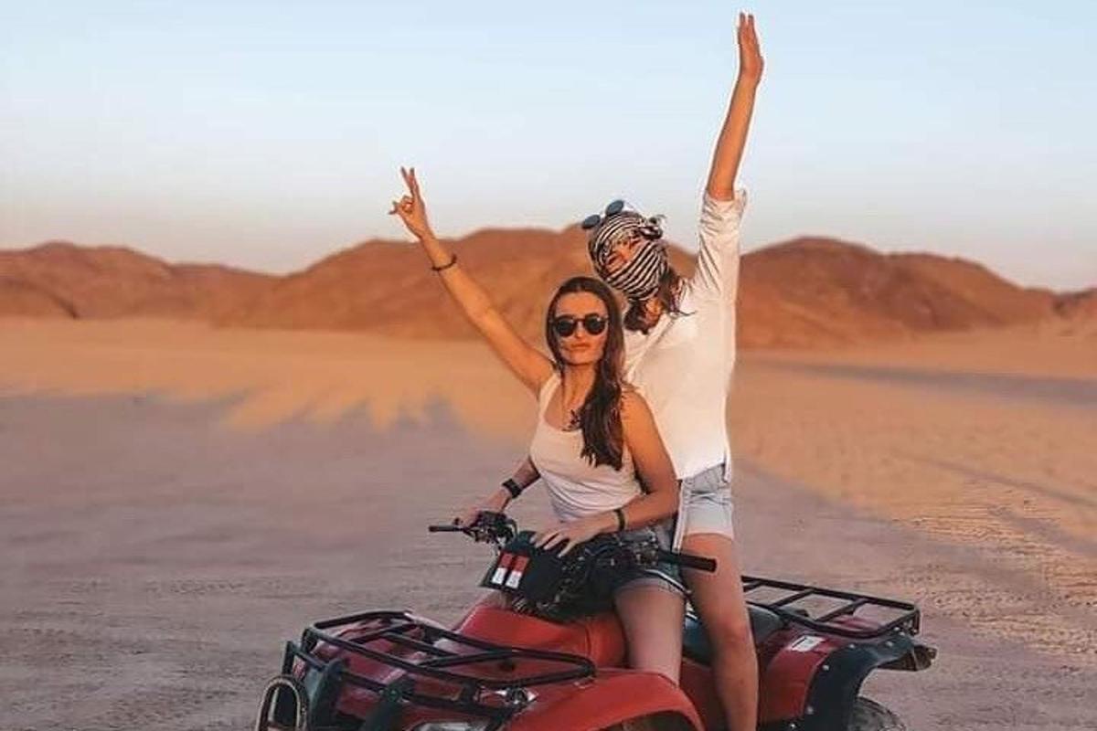 two people riding on a motorcycle in the desert