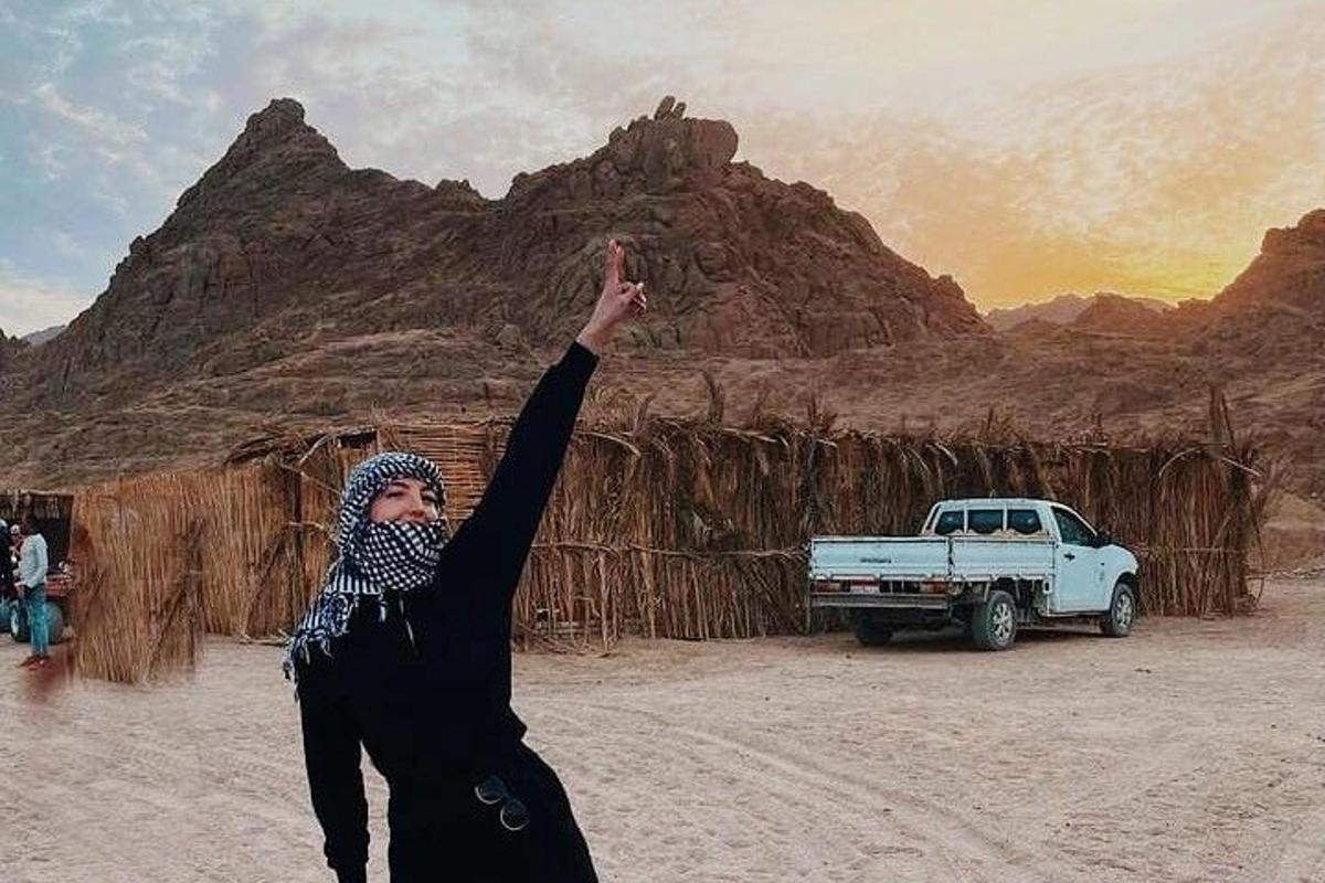 a woman standing in the desert with her hand in the air