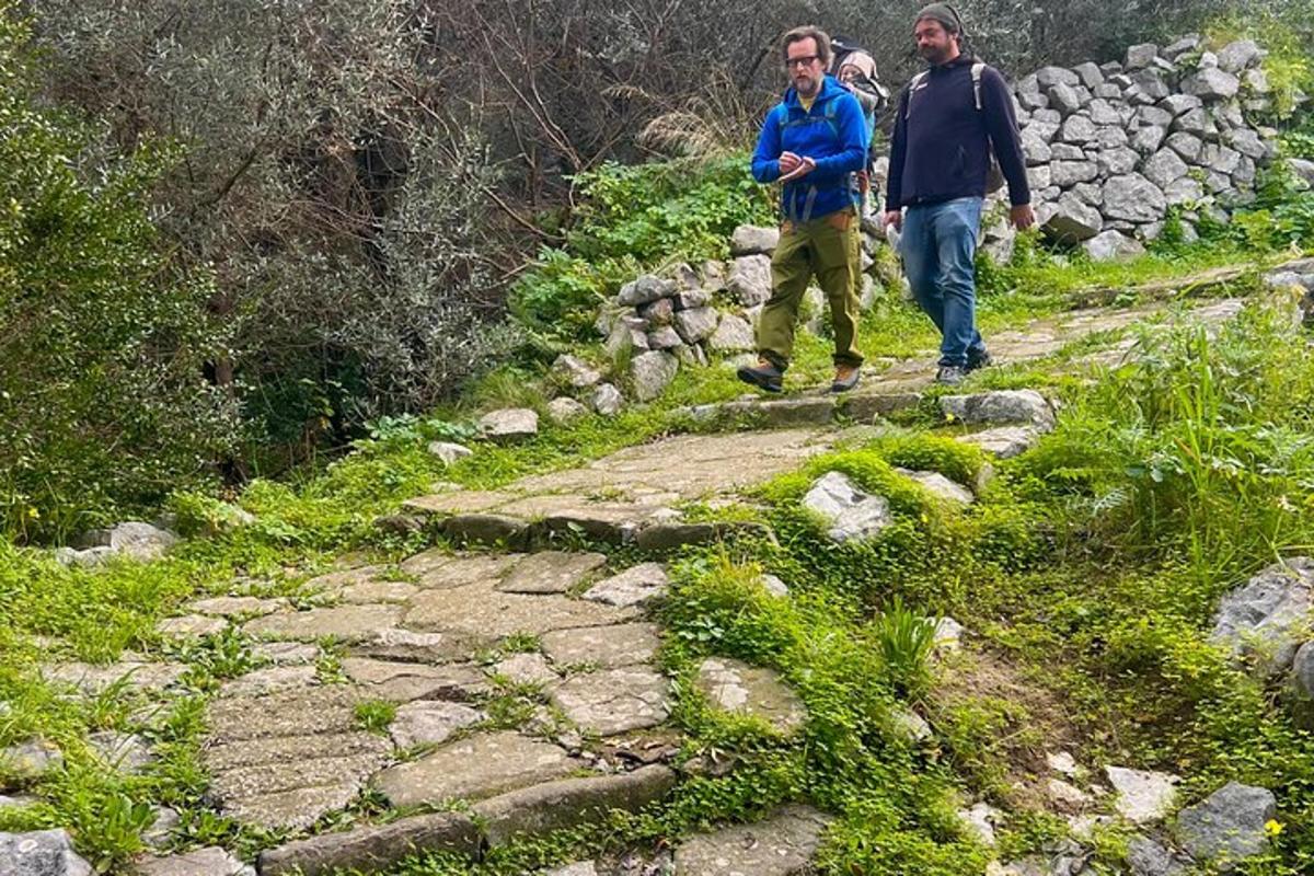 Dos hombres caminando por un sendero de piedra en una montaña