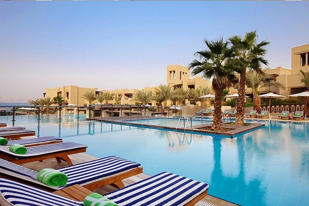a large swimming pool with lounge chairs and palm trees