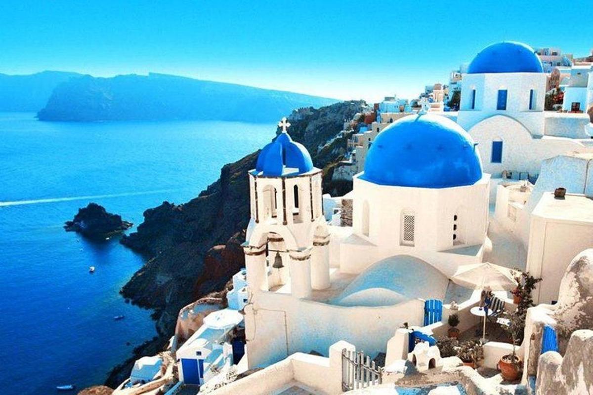 μια ομάδα λευκών κτιρίων με μπλε θόλους και τον ωκεανό