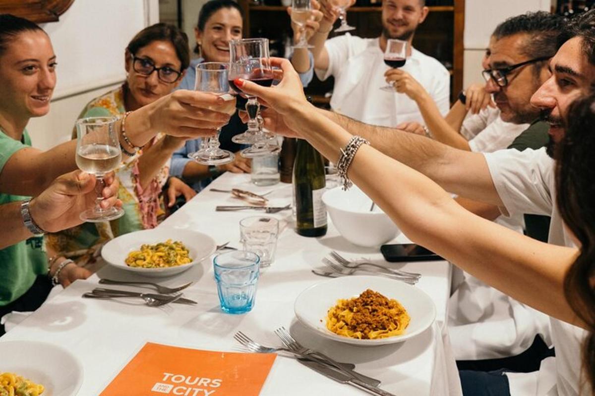 grupa ludzi siedząca przy stole i pijąca wino