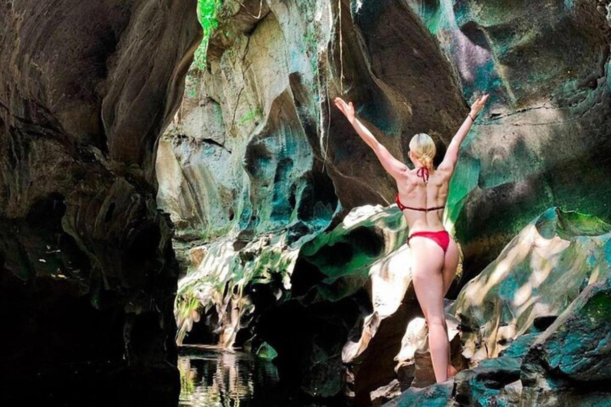 una dona en bikini dempeus sobre una roca a l'aigua